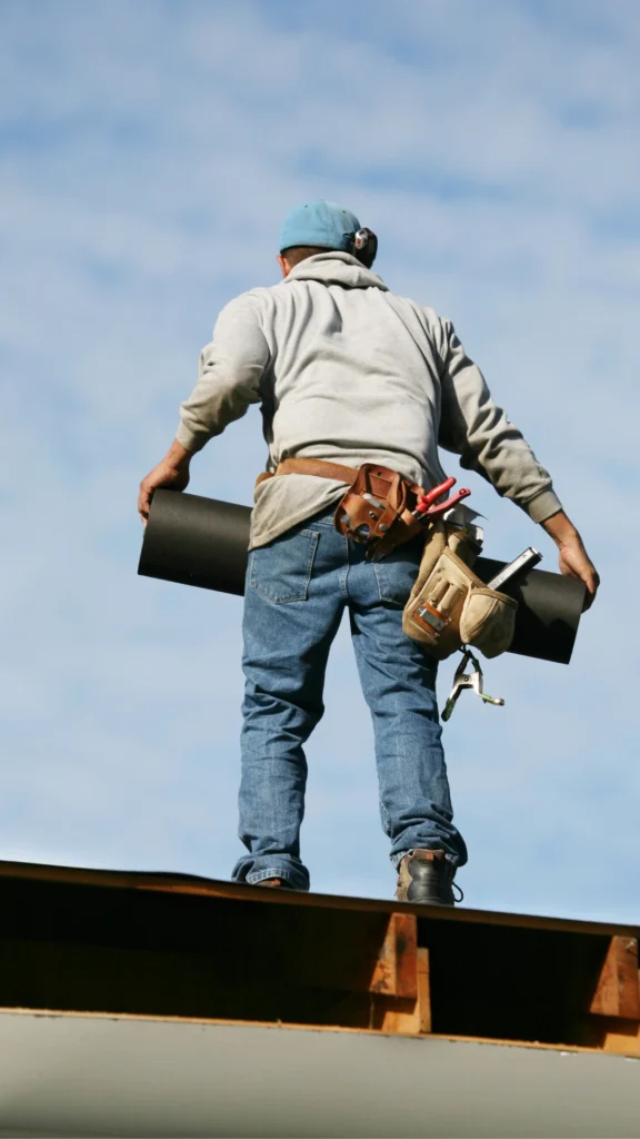 man on a roof carrying materials and tools 